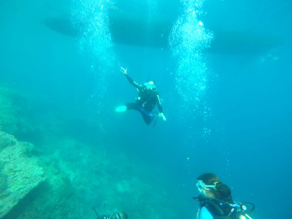 Divers descending through bubbles beneath a dive boat