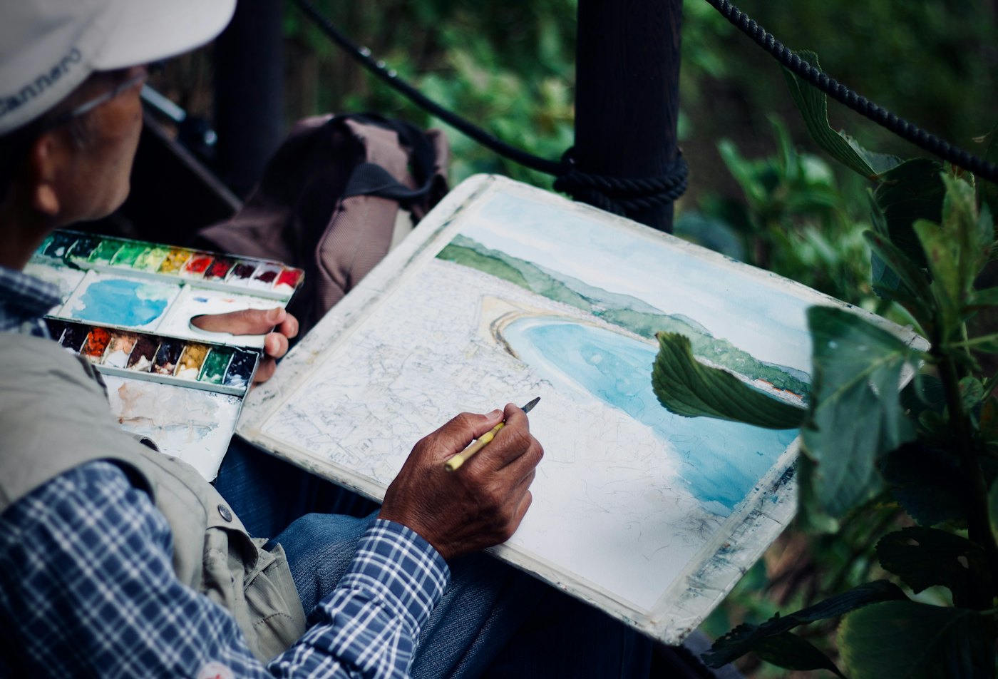A painter working on a seascape in watercolour outdoors