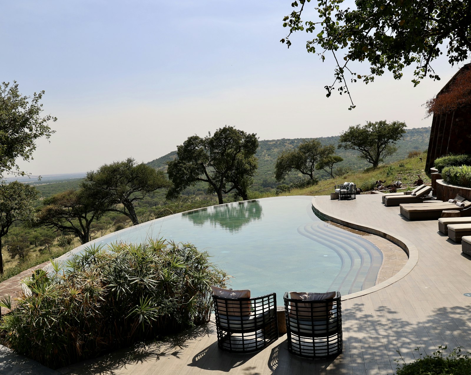 An infinity pool at a safari lodge overlooking green hills