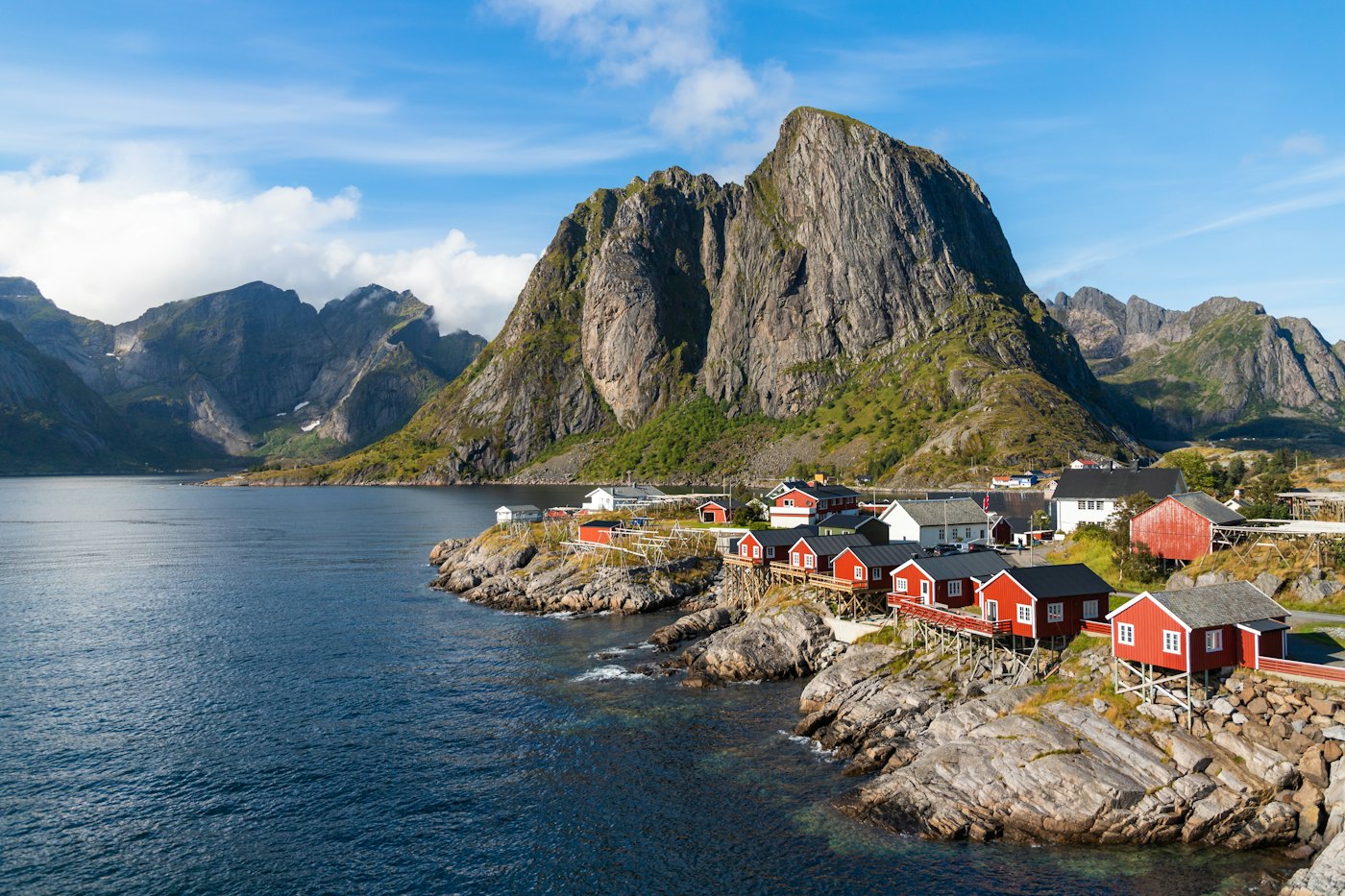 Red fishermen's cabins on the rocky shore beneath a granite peak in Lofoten